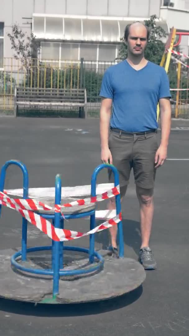 Vertikal. Seltsamer glatzköpfiger Mann steht auf einem leeren umzäunten Spielplatz — Stockvideo