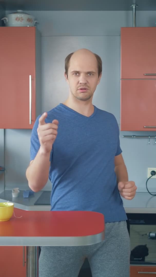 Dikey olarak. Tişörtlü kel adam mutfakta dans ediyor. — Stok video