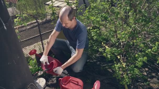 Uomo calvo versa acqua in un annaffiatoio da un barile in giardino — Video Stock