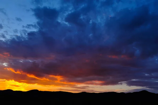 Bulutlu gün batımı, turuncu ve mor tonlarda.