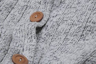 Giysiler, arka plan dokusu ekran koruyucular için ahşap düğmeli sıcak örülü ceket. Yünlü bir ürüne yakın çekim. Soğuk bir kış akşamında sıcacık ve samimi