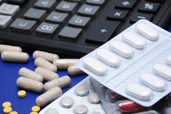 Leki Rozrzucone Niebieskim Tle Kalkulatorem Pigułki Różnych Kolorów — Zdjęcie stockowe