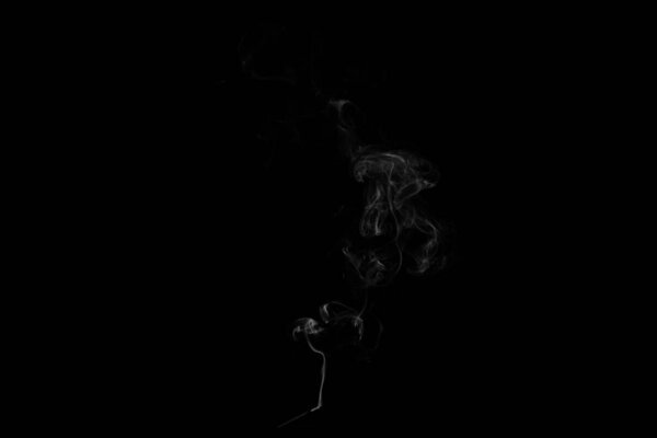 A stream of smoke on a white or black background, rises, bends and makes curls