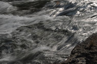 Öğleden sonra deniz kıyıları dalgalar ve su sıçramalarıyla, deniz kıyıları taşlarla.