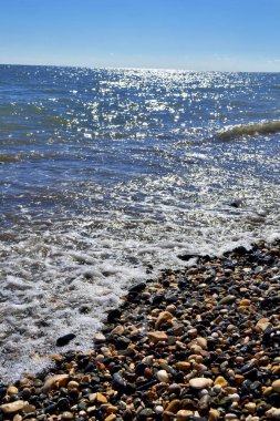 Öğleden sonra deniz kıyıları dalgalar ve su sıçramalarıyla, deniz kıyıları taşlarla.