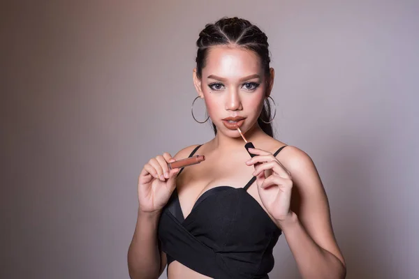 Cilt bakımı için temiz ve sağlıklı tenli Asyalı güzel gülümseyen kadın ve ürün ve tasarım için fotokopi alanı olan koyu arka planda kırmızı ruj tutan makyaj konsepti.