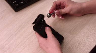 Kadın hesap makinesinin pilini değiştiriyor. Yakın plan: kadın elleri.