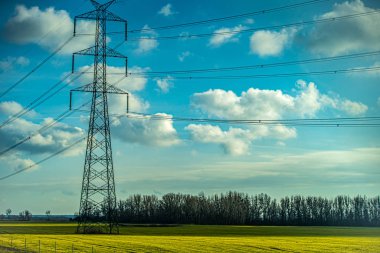 Elektrik direkleri ve yeşil alanları olan manzara.