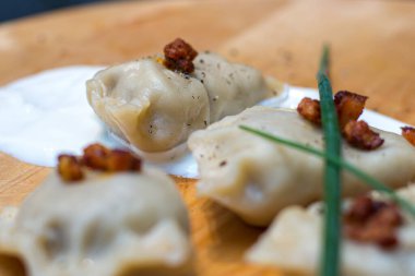 Pastırma ve kremalı ahşap bir tabakta hamur tatlısı. Pierogi. Polonya 'da geleneksel Noel arifesi yemeği Polonya' da