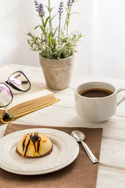 Still life with coffee, cake and a bouquet of lavender on white wooden table. Breakfast in the morning sun