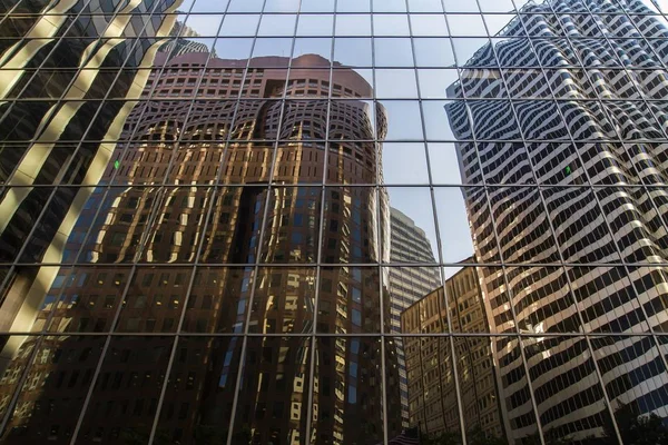 Los edificios de la ciudad se refleja en el cristal de un rascacielos al atardecer — Foto de Stock