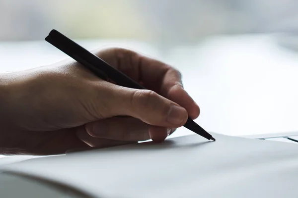 Een man die in een notitieblok schrijft. Sluit maar af. Gericht op een hand met pen — Stockfoto