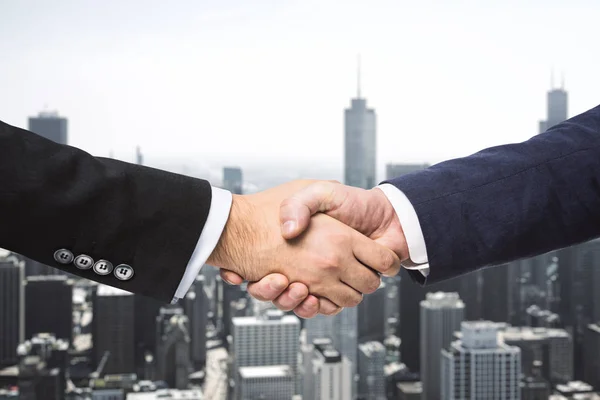 Two businessmen shake hands on a skyline background. Deal concept
