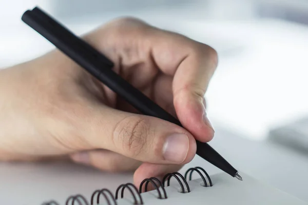 Een man die in een notitieblok schrijft. Sluit maar af. Gericht op een hand met pen — Stockfoto