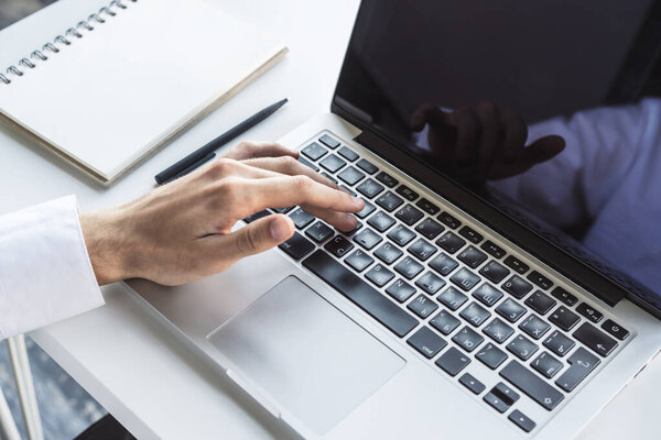 Closeup of male hand presses a button on laptop keyboard, working concept