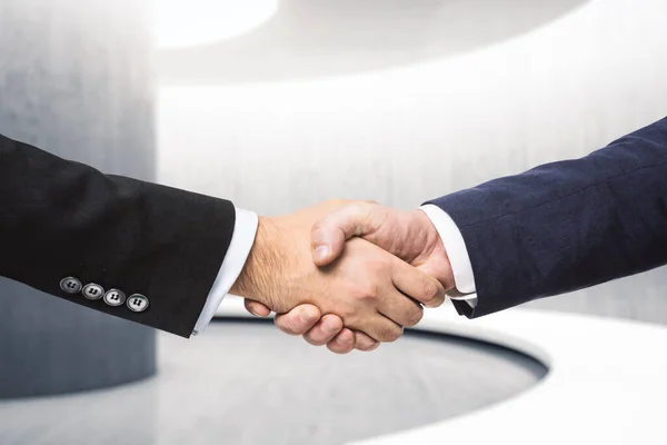 Two businessmen shake hands in the hallway, insider concept, close up