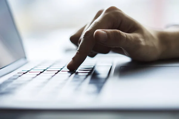 Male hands typing on laptop keyboard in sunny office, business and technology concept. Close up — Stock Photo, Image