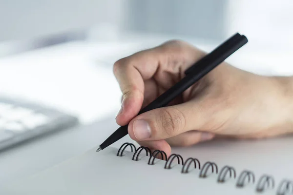 O homem escreve com uma caneta no caderno em um escritório ensolarado, conceito de negócios e educação. Fechar — Fotografia de Stock