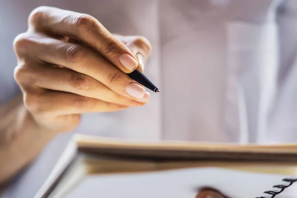 Empresária escreve de pé com uma caneta no diário em um escritório ensolarado, conceito de negócios e educação. Fechar — Fotografia de Stock