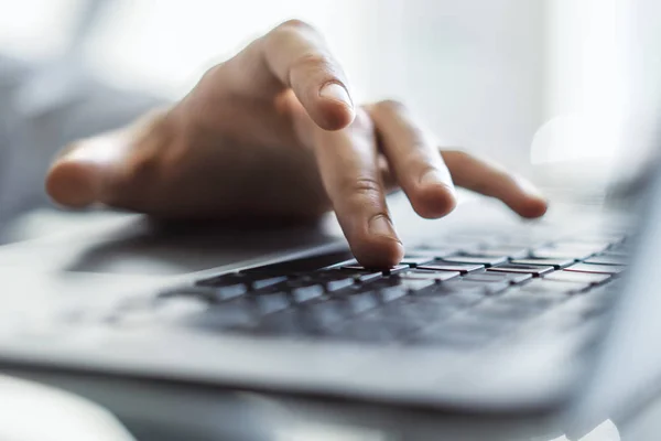 Male hands typing on laptop keyboard in sunny office, business and technology concept. Close up — Stock Photo, Image