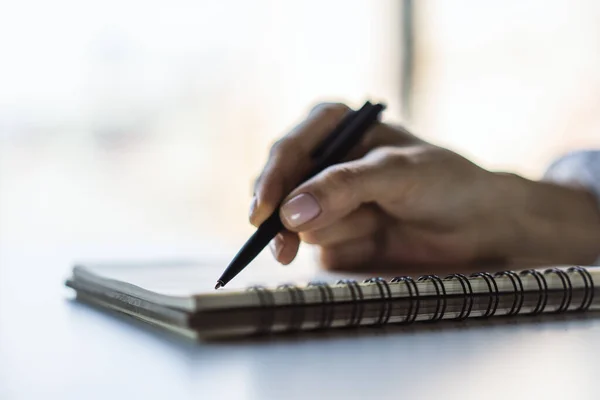 Жінка пише з ручкою в щоденнику в сонячному офісі, бізнес і освітній концепції. Зачиніть. — стокове фото