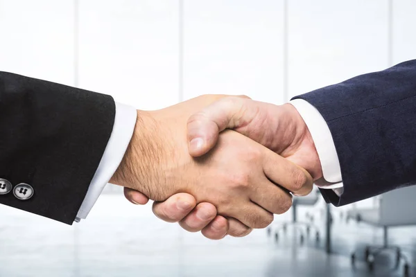 Два бизнесмена пожимают руки на фоне солнечного конференц-зала, концепция сделки, крупный план — стоковое фото
