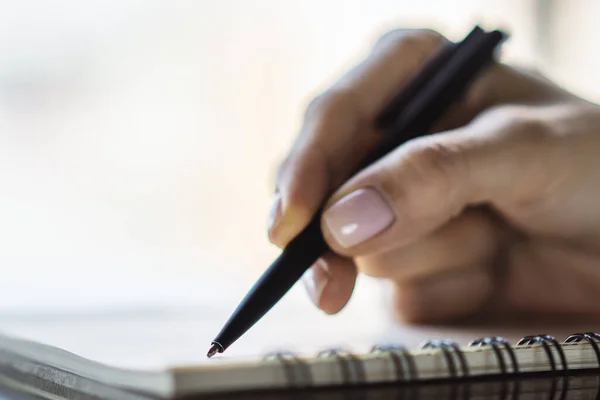 Vrouw schrijft met een pen in dagboek in een zonnig kantoor-, bedrijfs- en onderwijsconcept. Sluiten. — Stockfoto