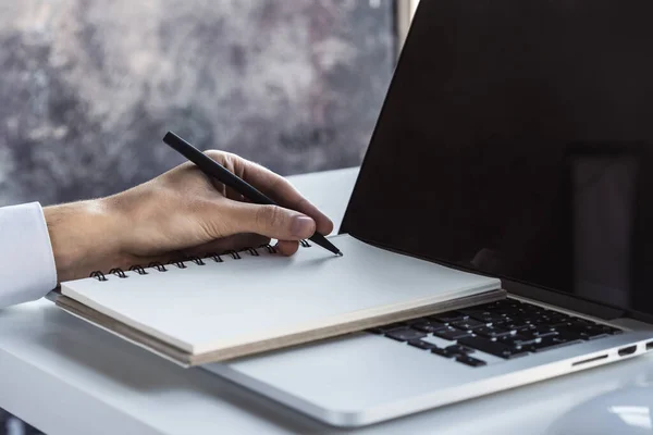 El hombre escribe con un bolígrafo en el portátil teclado en una oficina soleada, negocio y concepto de educación. De cerca. — Foto de Stock