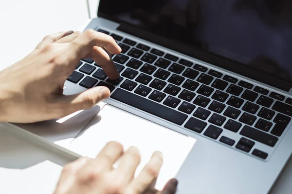 Empresario escribiendo en el teclado del ordenador portátil en la oficina soleada, concepto de negocio y tecnología. De cerca. — Foto de Stock