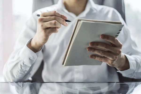 Man writes with a pen in diary in a sunny office, business and education concept. Close up