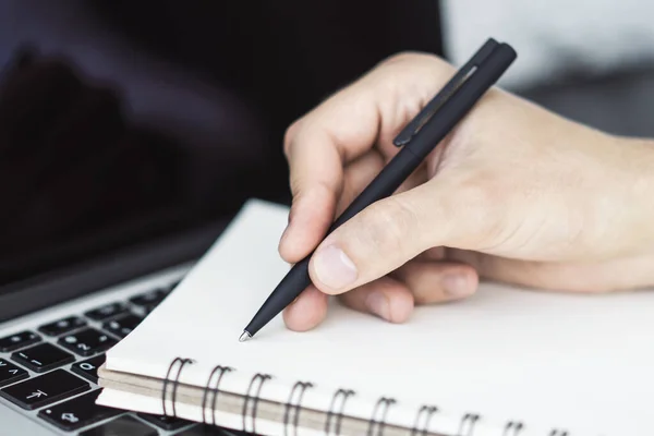 Empresario escribe con un bolígrafo en el diario en el teclado del ordenador portátil en una oficina soleada, negocio y concepto de educación. De cerca. — Foto de Stock