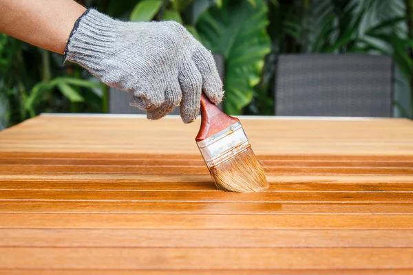 Кисть в руке и покраска на деревянном столе — стоковое фото