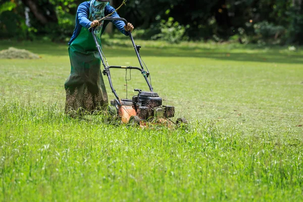 Ein Arbeiter mäht Gras im Garten — Stockfoto