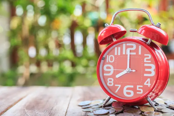 Czerwony alarm clock i kupie monety na drewniane deski — Zdjęcie stockowe