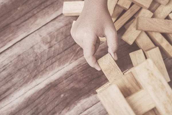 Mano sosteniendo bloques juego de madera (jenga) sobre fondo de madera tablón —  Fotos de Stock