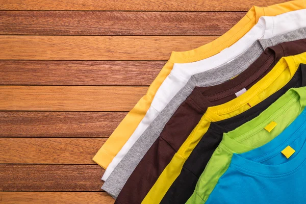 Bovenaanzicht van kleur T-Shirt op grijze houten plank — Stockfoto