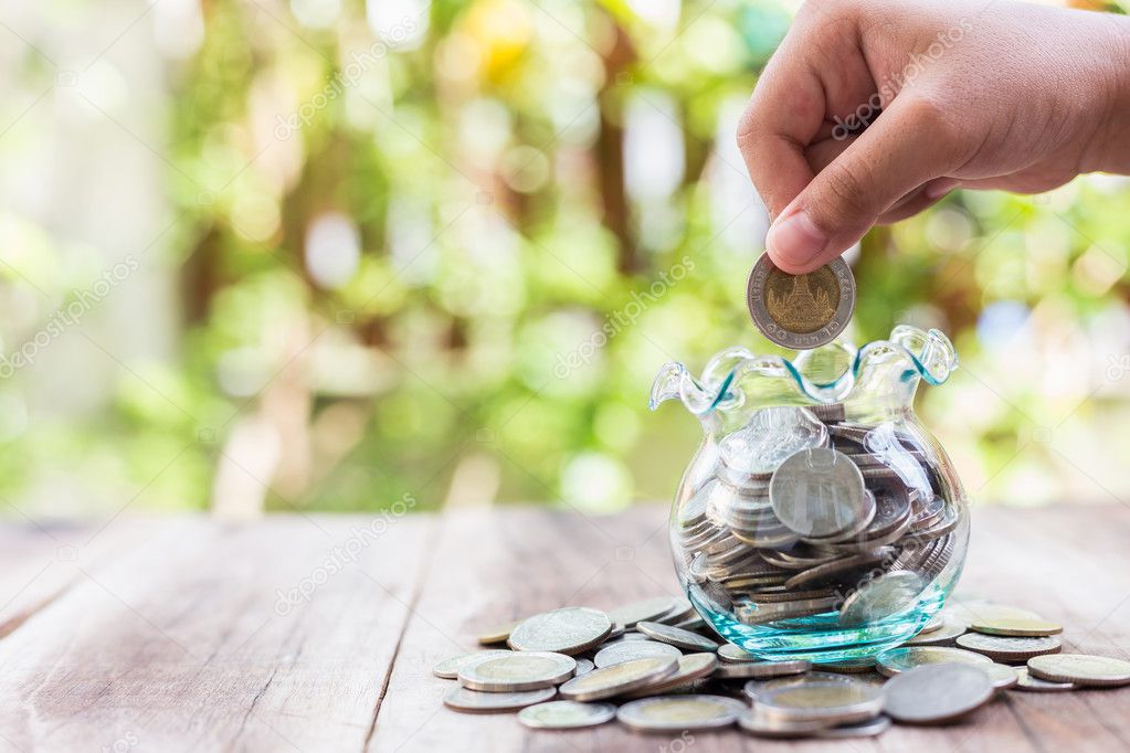 Hand putting coins in money jar. savings concept.