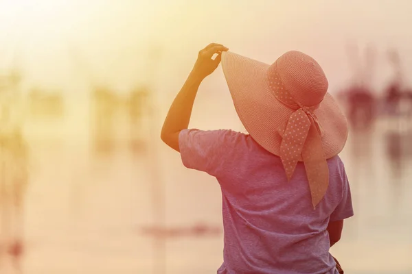 Hinterseite einer Frau mit großem Hut auf der Brücke und Sonnenaufgang — Stockfoto