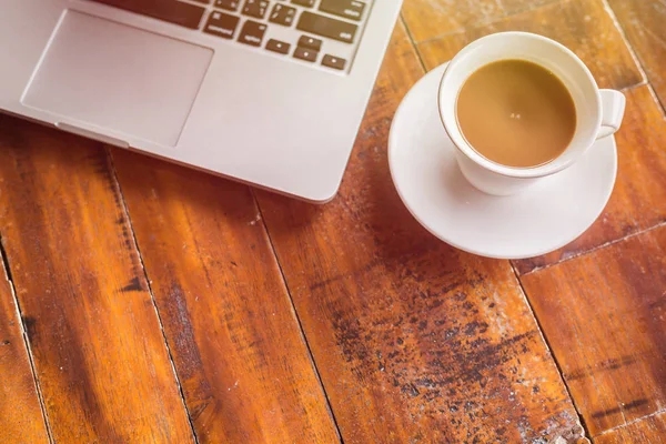 Tazza di caffè bianco e laptop su tavolo in legno vista dall'alto — Foto Stock