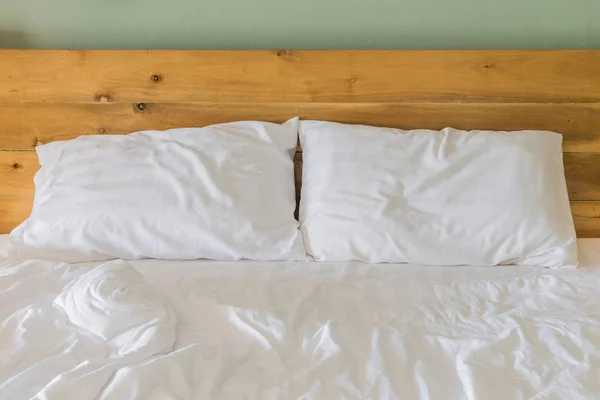Білі простирадла для постільної білизни та подушка на фоні дерев'яної стіни кімнати , — стокове фото