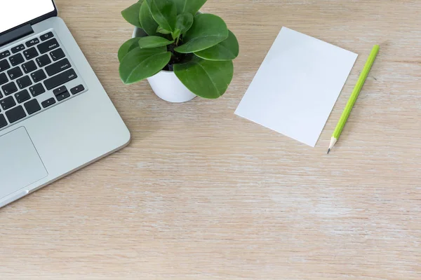 Laptop med tomt vitt papper på trä skrivbord — Stockfoto