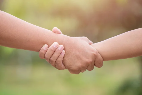 Zwei Hände, die zusammenhalten. Hilfe- oder Unterstützungskonzept. auf grünem Grund — Stockfoto