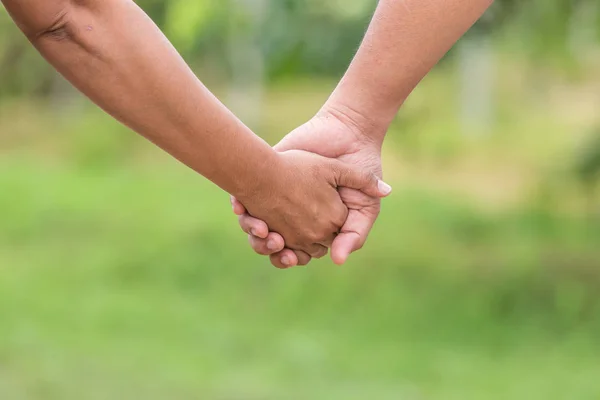 Zwei Hände, die zusammenhalten. Hilfe- oder Unterstützungskonzept. auf grünem Grund — Stockfoto