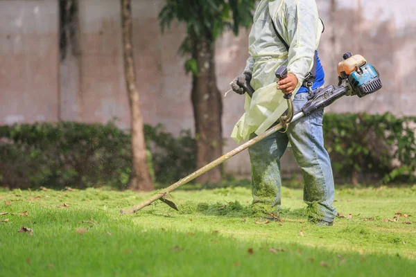 庭で携帯機で草を刈る男 — ストック写真