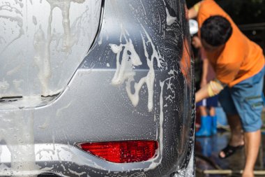 Araba araba bakım dükkanda yıkama için SOAP'ı kullanarak bir adam