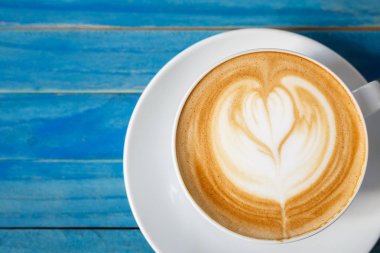 Üstten Görünüm sıcak latte kahve mavi vintage ahşap üzerinde beyaz Kupası'nda ta