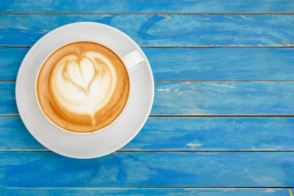 Top vista café quente latte em copo branco em azul vintage de madeira ta — Fotografia de Stock