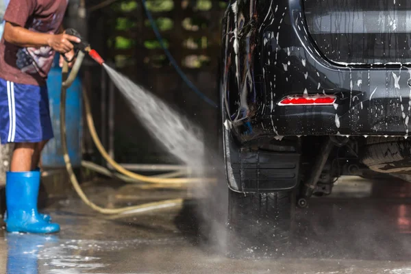 Un homme pulvérisant lave-pression pour lavage de voiture dans l'atelier de soins de voiture — Photo