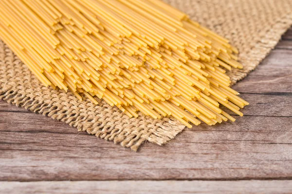 Żółty długi spaghetti, spaghetti surowy na drewniane — Zdjęcie stockowe