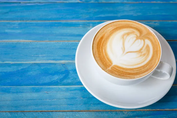 Von oben heißen Latte-Kaffee in weißer Tasse auf blauem Vintage-Holz ta — Stockfoto